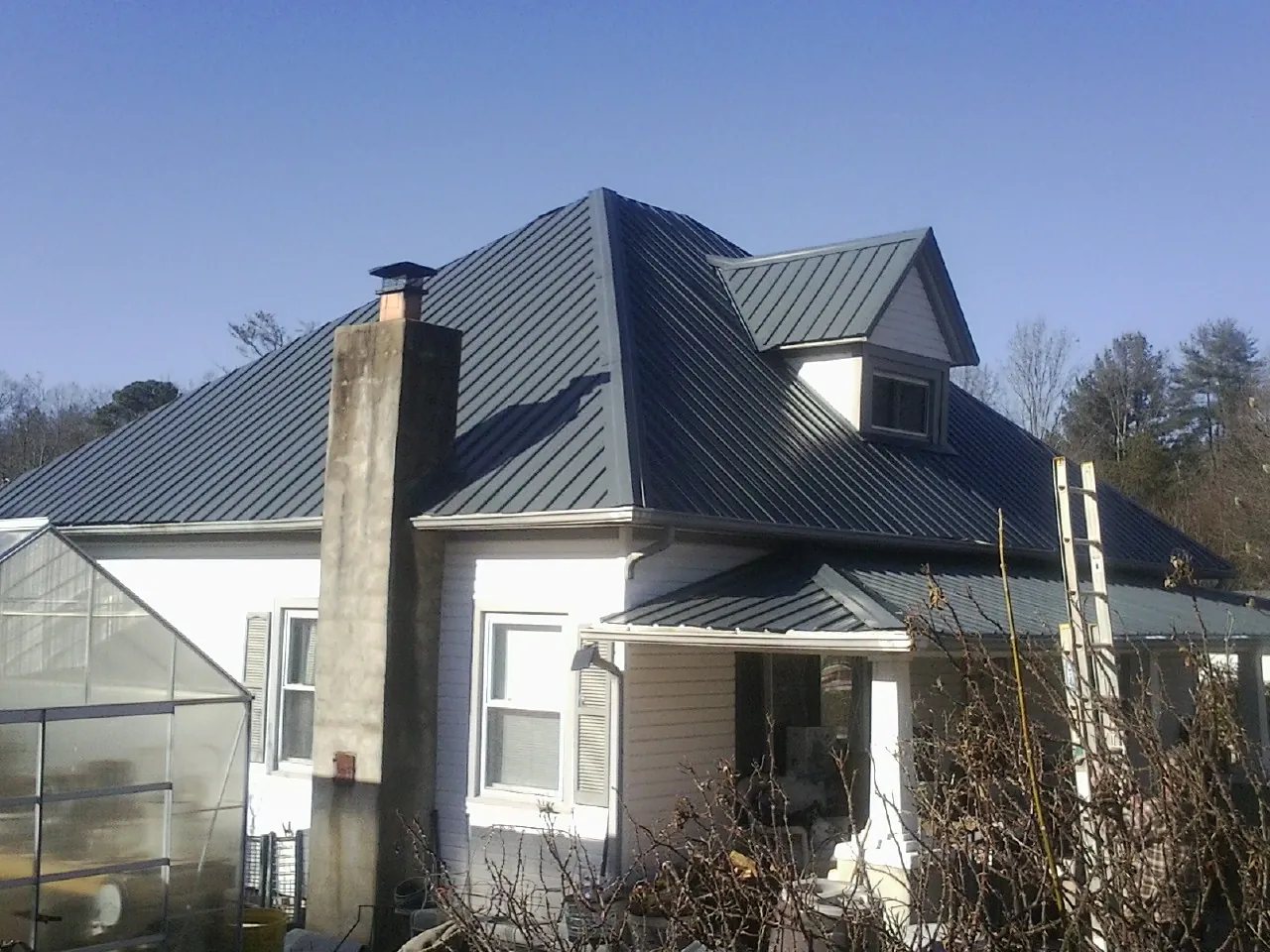 Dark blue standing seam metal roof on a white farmhouse with dormer — Slate & Tile Roof Repair by Roofing Brothers in Souderton