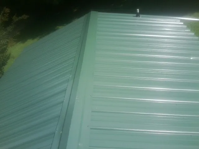New green metal panels meeting at the ridge of a roof — Flat Roof Repair work by our crew in Souderton