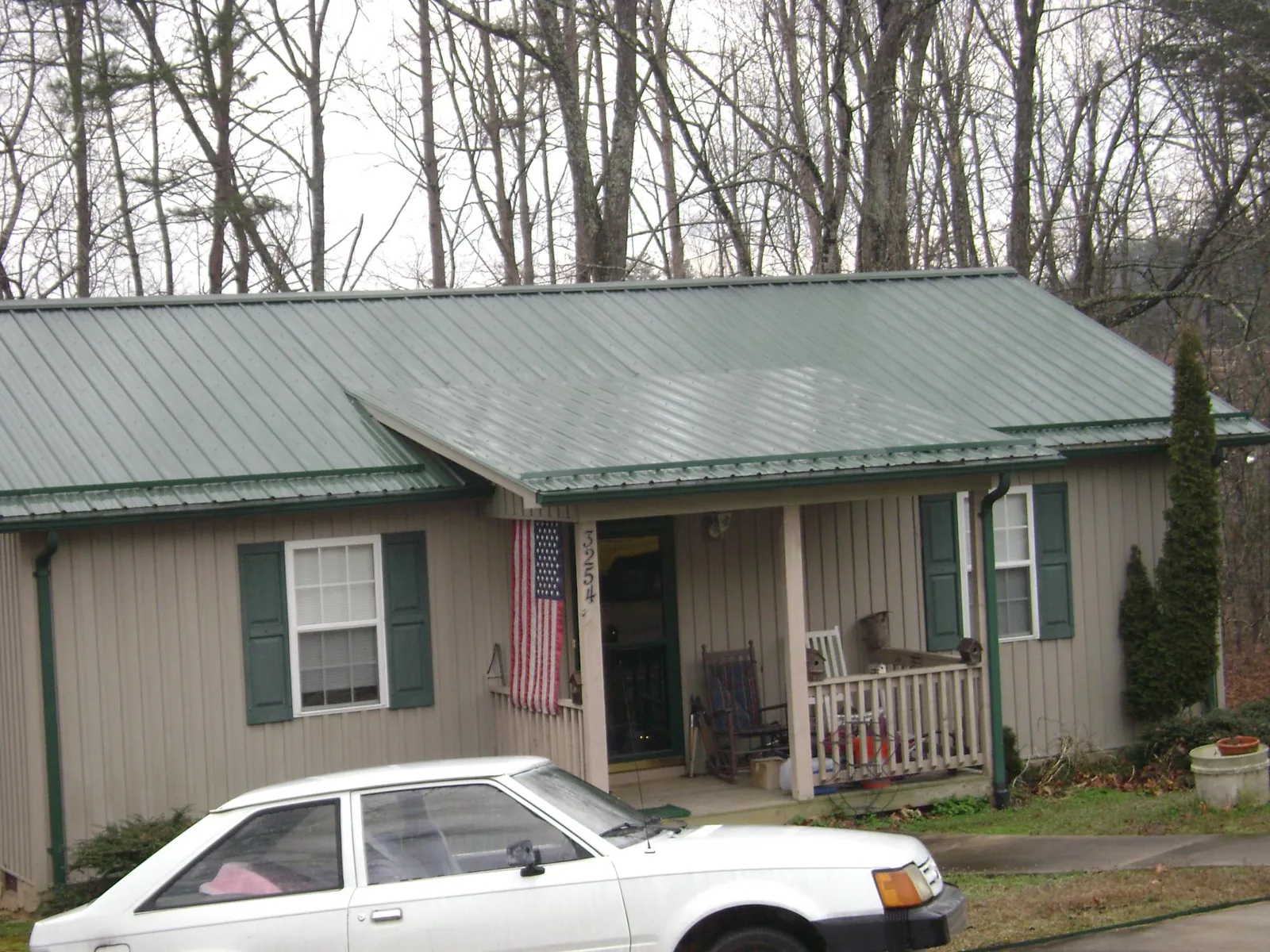 Green metal roof and front porch on a tan sided cottage in Souderton