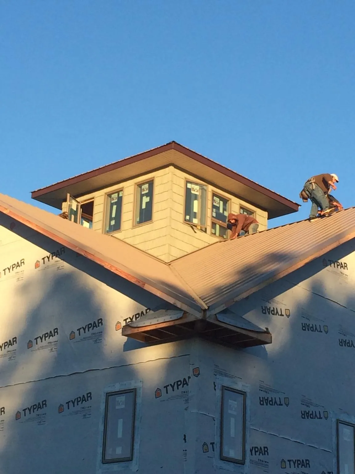 Roofers working around a rooftop cupola on a new metal roof at sunset — Roof Waterproofing in Souderton by Roofing Brothers
